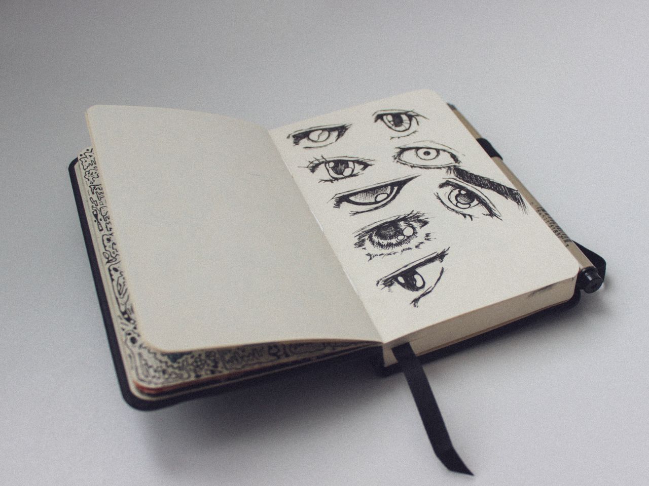 About A sketchbook open to a page with artistic eye drawings, showcasing detailed sketches.