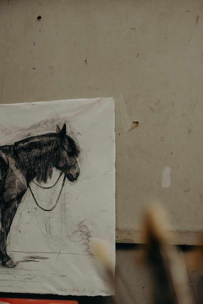 A detailed charcoal sketch of a horse hangs on a textured wall, creating a fine art ambiance.
