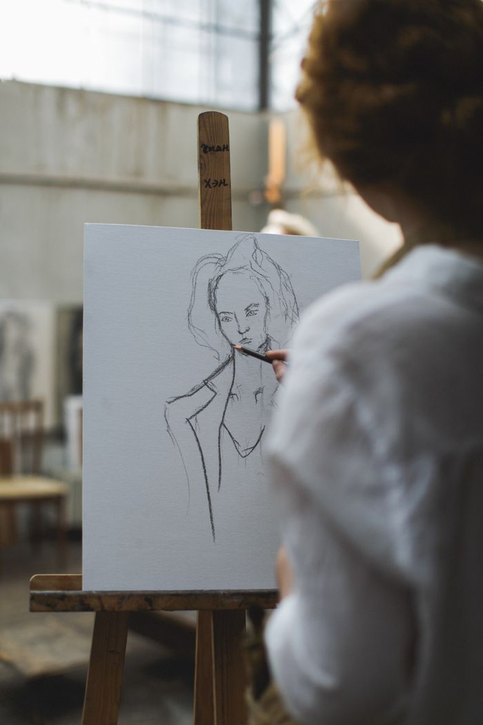 Artist sketching a portrait on canvas in an art studio, showcasing creativity and technique.
