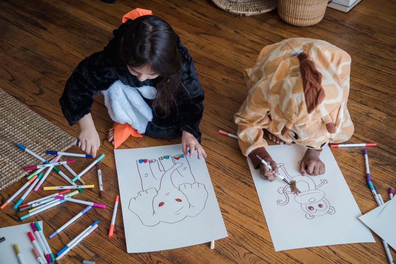 Offerings Children in animal costumes drawing on paper with colorful markers indoors.